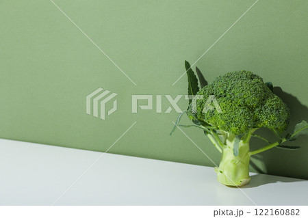 Branch of broccoli on table on green background, space for text 122160882
