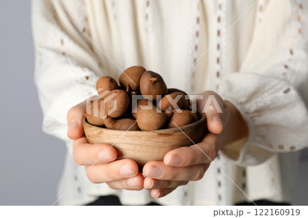 Ripe tamarind in a wooden bowl in female hands 122160919
