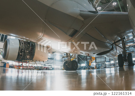 Close-up of the lower fuselage of a white passenger jet plane in an aircraft hangar. Airplane under maintenance. Checking mechanical systems for flight operations 122161314