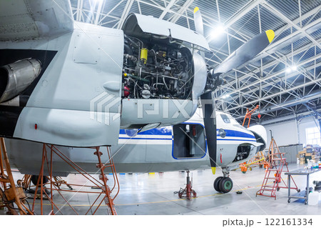 Transport turboprop aircraft in the hangar. Close-up of an open airplane engine. Checking mechanical systems for flight operations Transport turboprop aircraft in the hangar. Close-up of an open airplane engine. Checking mechanical systems for flight operations 122161334