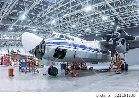 Transport turboprop aircraft in the hangar. Airplane under maintenance. Checking mechanical systems for flight operations Transport turboprop aircraft in the hangar. Airplane under maintenance. Checking mechanical systems for flight operations 122161339