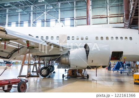 White passenger jet plane in the hangar. Jetliner under maintenance. Checking mechanical systems for flight operations 122161366