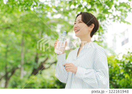 新緑の中で水分補給する女性 122161948