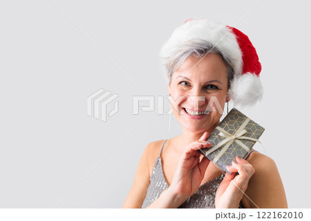 An elderly middle-aged lady with gray hair and a short haircut smiles and holds a gift. 122162010