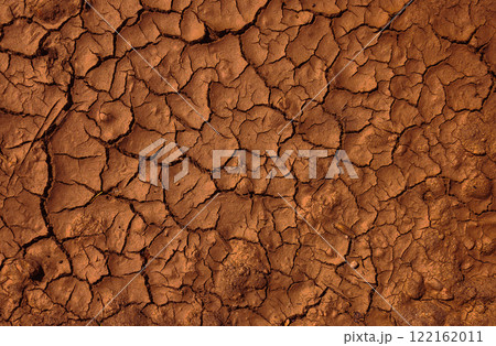 The cracked, dry earth surface showcases a unique texture filled with warm brown tones. Climate change, drought 122162011