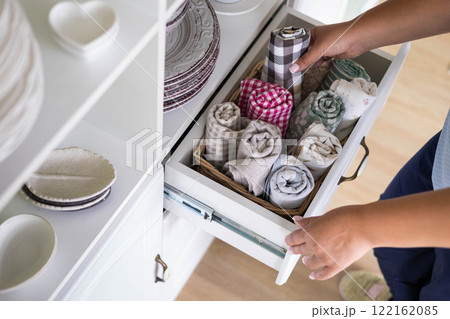 Woman placing kitchen textile towel roll in whicked basket shelf rustic retro commode top view Woman placing kitchen textile towel roll in whicked basket shelf rustic retro commode top view 122162085