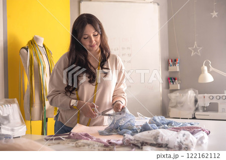 A woman seamstress designs and draws a pattern for underwear on graph paper.  122162112