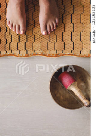 Yoga woman legs standing on nails with singing meditation bowl top view closeup Yoga woman legs standing on nails with singing meditation bowl top view closeup 122162135