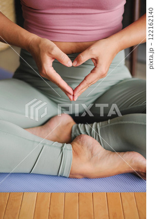 Yoga woman in lotus position with hands heart shape closeup. Yogi spiritual female asana with love 122162140