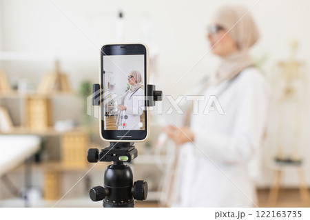 Muslim woman in hijab, adult, records medical tutorial on setting up intravenous drip for patient using smartphone. Educational and informative content creation in healthcare setting. 122163735