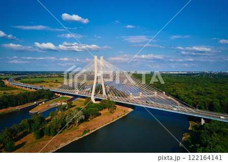 Cable stayed bridge over river surrounded by lush green forest. Redzinski bridge over Odra river with cars driving on highway in Wroclaw, Poland 122164141