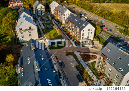 Aerial view of modern residential neighborhood with contemporary apartment buildings, green spaces, parking areas and well-maintained pathways on sunny day 122164183