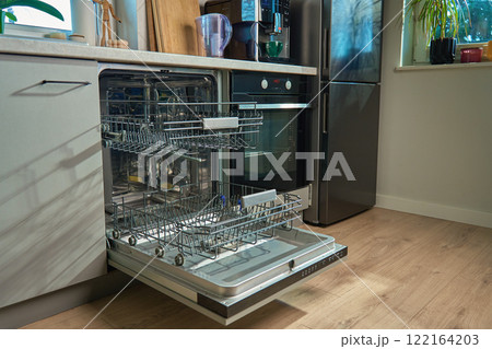 Open empty dishwasher with empty racks and extended basket in modern kitchen ready for loading. Home appliance Open empty dishwasher with empty racks and extended basket in modern kitchen ready for loading. Home appliance 122164203