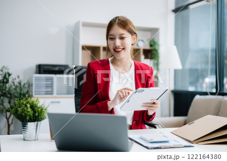 Asian businesswoman working with working notepad, tablet and laptop documents in the office Asian businesswoman working with working notepad, tablet and laptop documents in the office 122164380