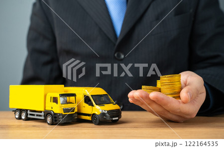 Businessman holds stacks of coins in outstretched hand and truck with delivery van. Profit from the transport company, industry. Profitability of courier deliveries and transportation. Businessman holds stacks of coins in outstretched hand and truck with delivery van. Profit from the transport company, industry. Profitability of courier deliveries and transportation. 122164535