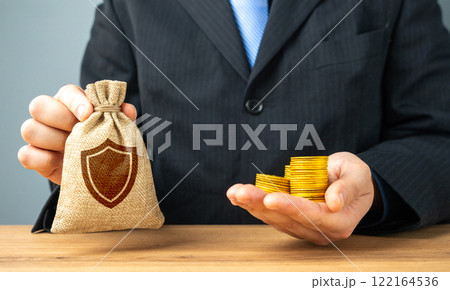 Man holding coins and bag with security shield symbol. Concept of protection and security. Insurance. 122164536