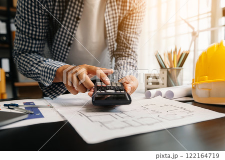 Engineer in helmet for workers security on office buildings and management on the construction drawing plan near laptop working in Engineering tools Engineer in helmet for workers security on office buildings and management on the construction drawing plan near laptop working in Engineering tools 122164719