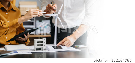 Alternative energy engineer pointing to a solar power panel and discuss with  business colleague team for the future power in the office 122164760