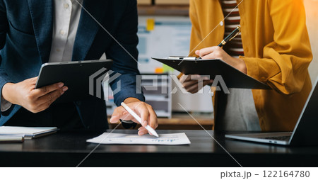 Businessman and team analyzing financial statement Finance task. with smart phone and laptop and  tablet. Wealth management concept in office 122164780
