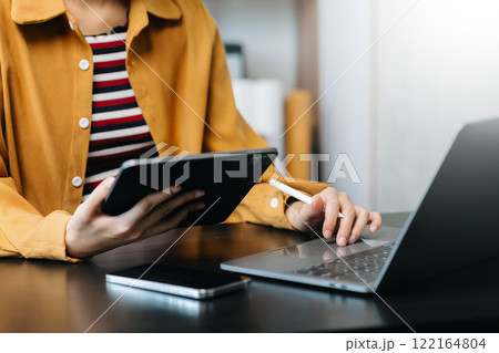 Hands of woman using mobile phone in modern office with laptop and digital tablet at home office Hands of woman using mobile phone in modern office with laptop and digital tablet at home office 122164804