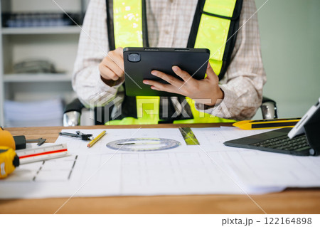 Businessman hand working and laptop with on on architectural project at construction site 122164898