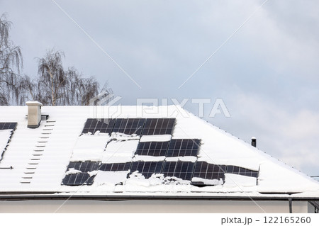 Solar panels covered in snow on the roof of a house 122165260