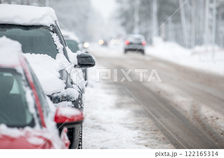 Winter driving conditions, snowy roadway and parked cars at side of road Winter driving conditions, snowy roadway and parked cars at side of road 122165314