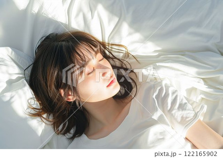 ベッドで寝ている日本人女性のポートレート（睡眠・うたたね・寝る・快眠・休息）	 122165902