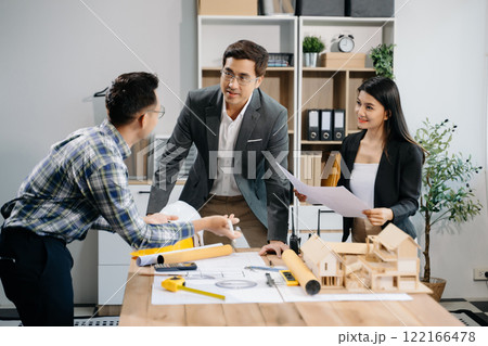 Engineer teams meeting working together wear worker helmets hardhat with on architectural project site and making model house. 122166478