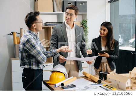 Engineer teams meeting working together wear worker helmets hardhat with on architectural project site and making model house. 122166566