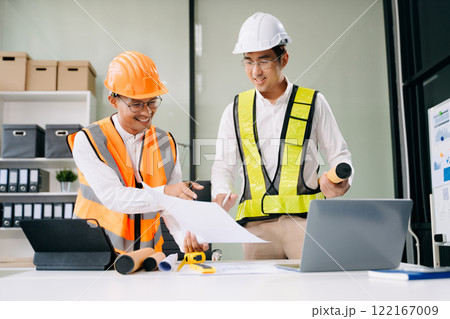 Contractor and architect looking at plan, tablet, laptop and talking about working on big project. 122167009