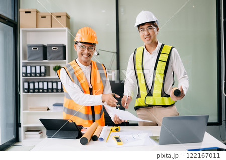 Contractor and architect looking at plan, tablet, laptop and talking about working on big project. 122167011