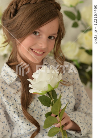 Pretty little girl smiling and posing with flowers Pretty little girl smiling and posing with flowers 122167460