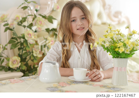 Smiling little girl holding big cup of tea 122167467