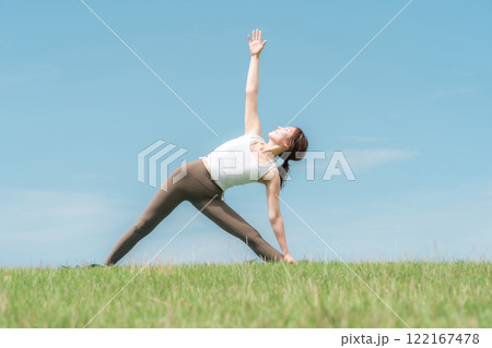青空の下でヨガ・ピラティス・ストレッチをする若いアジア人女性 122167478