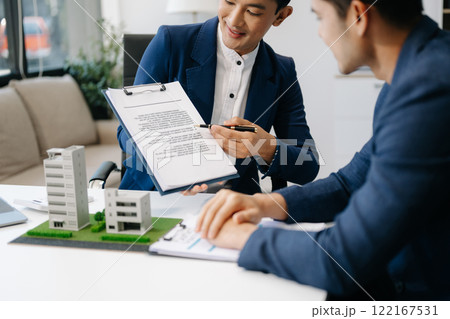 balancing the property sector The real estate agent is explaining the house style to see the house design and the purchase agreement. model house balancing the property sector The real estate agent is explaining the house style to see the house design and the purchase agreement. model house 122167531