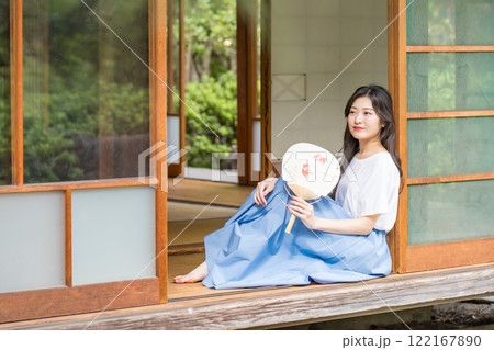 古民家の縁側に座って、団扇で扇いで涼む若い女性 古民家の縁側に座って、団扇で扇いで涼む若い女性 122167890