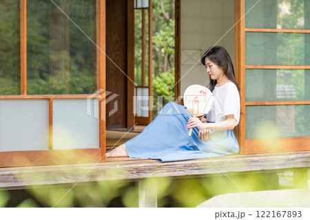 古民家の縁側に座って、団扇で扇いで涼む若い女性 古民家の縁側に座って、団扇で扇いで涼む若い女性 122167893