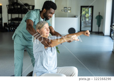 Male therapist helping patient with physical therapy exercises for pain relief and recovery Male therapist helping patient with physical therapy exercises for pain relief and recovery 122168290