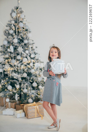 Cute little girl with gift in box and christmas tree 122169657