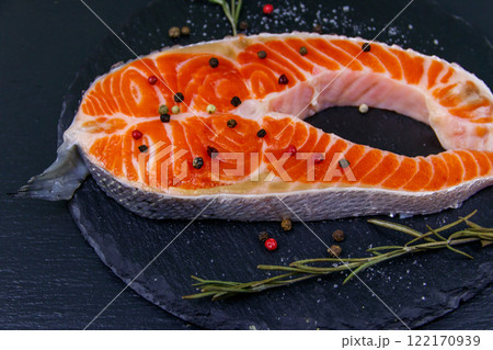 Raw salmon steak with spices on black slate Raw salmon steak with spices on black slate 122170939