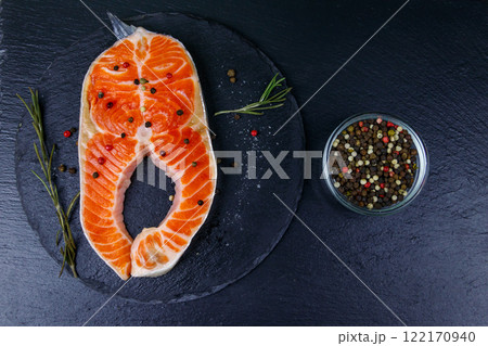 Raw salmon steak with spices on black slate. Top view 122170940