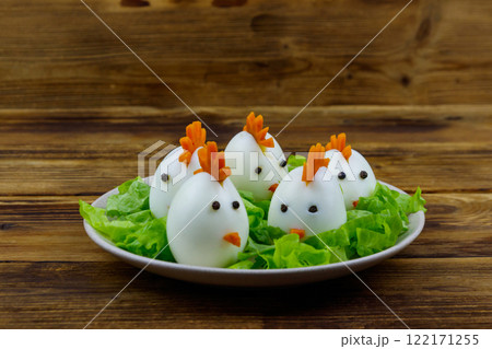 Funny easter breakfast with boiled eggs as chicks on wooden table Funny easter breakfast with boiled eggs as chicks on wooden table 122171255