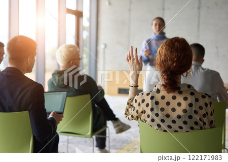 A diverse group of business professionals sits attentively in a modern office, actively participating in a training session led by an instructor, focusing on the latest technological advancements in 122171983