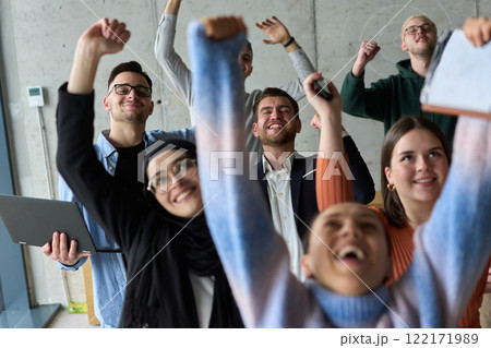 A diverse team of business professionals ecstatically celebrating their success in a modern office, expressing triumph and unity after achieving their goals 122171989