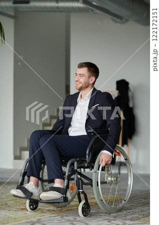 A businessman in a wheelchair enjoys a moment of laughter by a large window in a modern office, embodying positivity, resilience, and a balanced approach to work and life. A businessman in a wheelchair enjoys a moment of laughter by a large window in a modern office, embodying positivity, resilience, and a balanced approach to work and life. 122172151