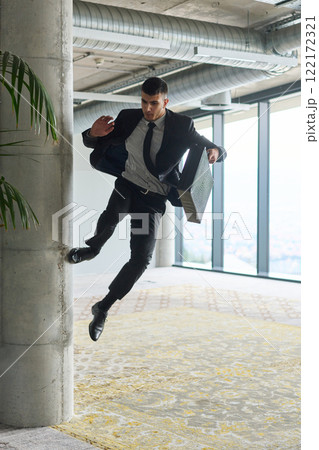 A businessman ecstatically jumping in a modern office, holding a briefcase in his hands, celebrating a moment of success and triumph. A businessman ecstatically jumping in a modern office, holding a briefcase in his hands, celebrating a moment of success and triumph. 122172321
