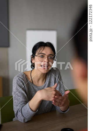 A close up portrait of a young businesswoman engaged in a professional meeting, confidently discussing ideas and strategies with her colleagues A close up portrait of a young businesswoman engaged in a professional meeting, confidently discussing ideas and strategies with her colleagues 122172346