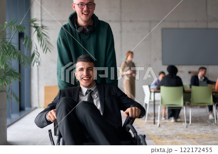 Employee Entertaining Director in a Wheelchair While Rolling Through the Office with Laughter and Joy. 122172455