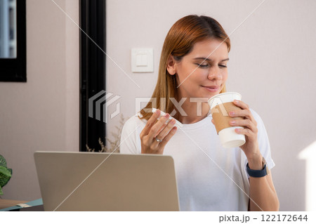 Happiness young caucasian businesswoman drinking coffee while working on laptop computer. 122172644